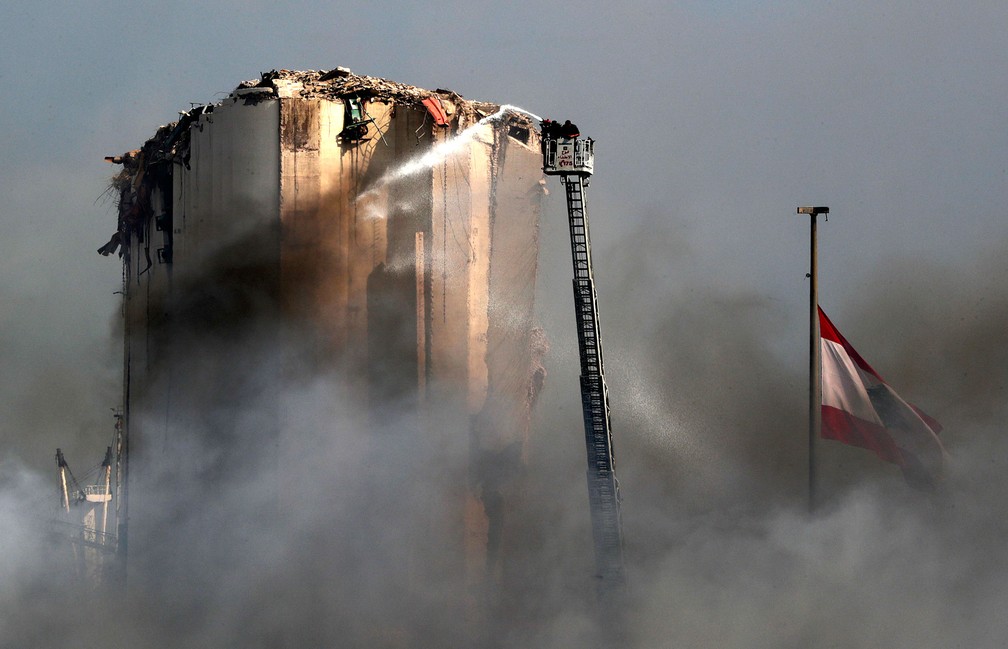 Bombeiros usam escada em operação para extinguir incêndio no porto de Beirute, no Líbano, nesta sexta-feira (11)  — Foto: Anwar Amro / AFP