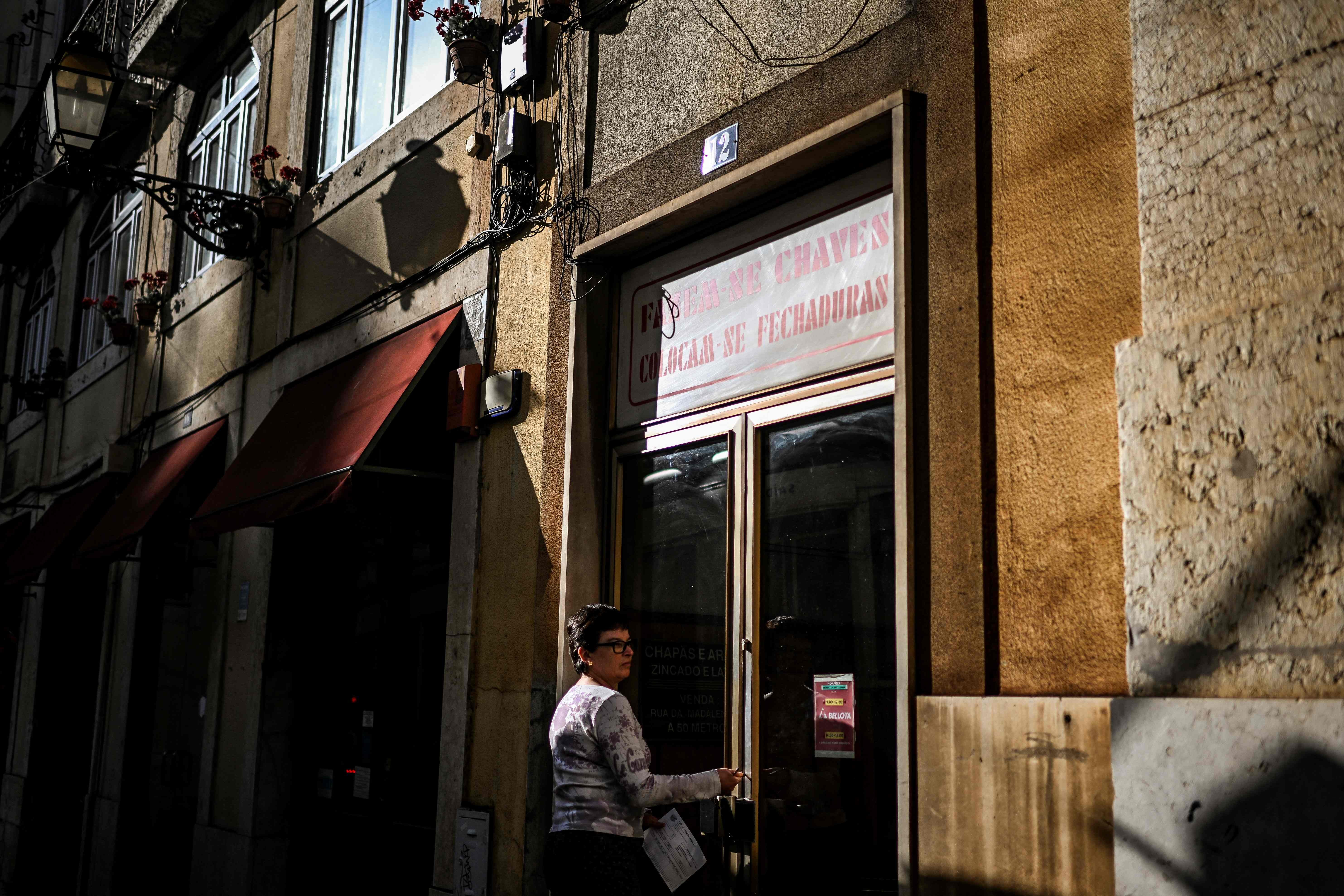 Mulher fecha uma loja na área de Alfama, Lisboa