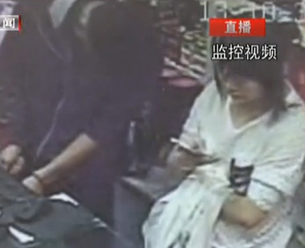 Cansada de consecutivos assaltos, funcionária joga no celular enquanto loja é roubada (Foto: Reprodução/Youku/Beijing Television)
