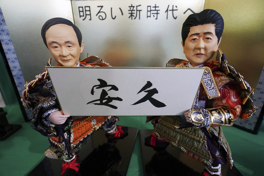 Bonecos tradicionais japoneses mostram o chefe de gabinete japonês, Yoshihide Suga (à esquerda), e o primeiro-ministro, Shizo Abe,  segurando uma placa com o nome da nova era imperial japonesa, Reiwa, revelado no dia 1º de abril. — Foto: AP Photo/Eugene Hoshiko