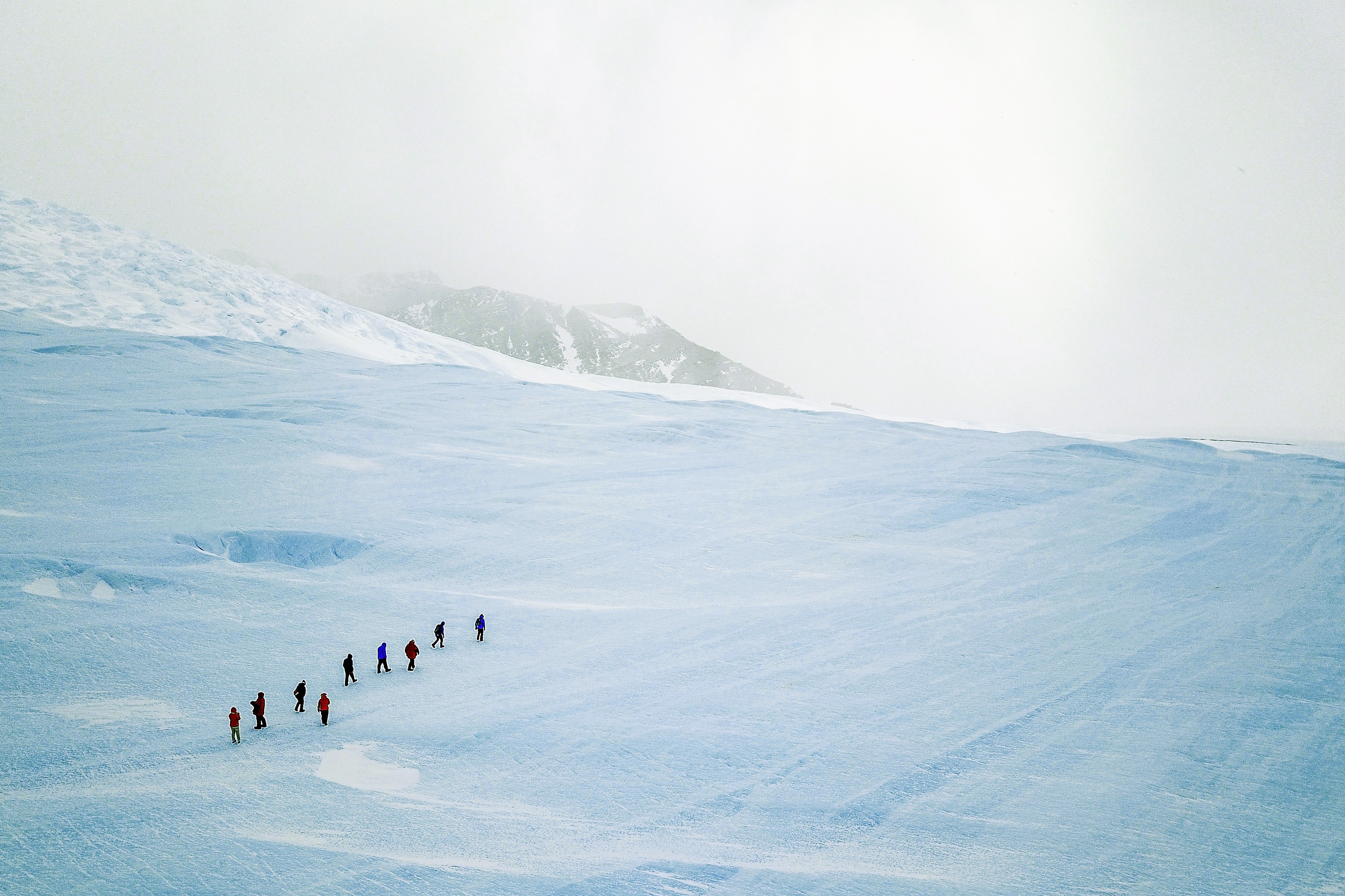 A group of guests hike up blue-ice during an excursion to the Drake Icefall on an overcast day. (Foto: Photo Credit: Christopher Michel)