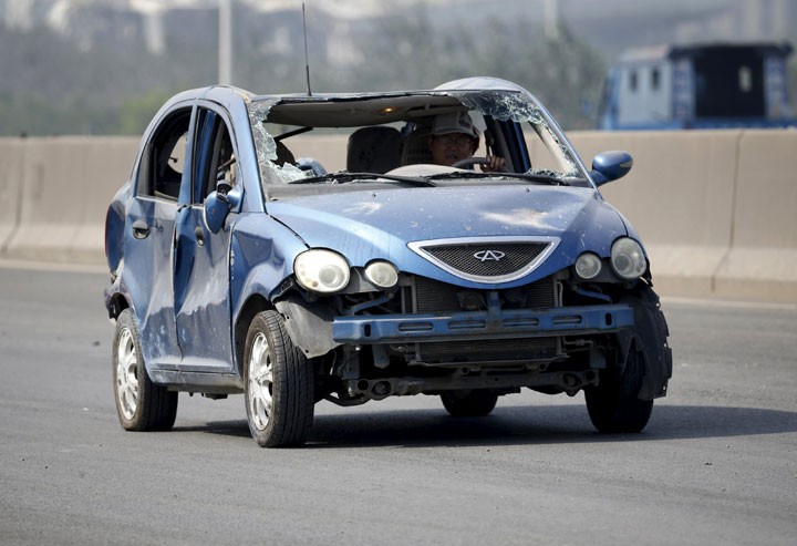 Motorista conduz carro danificado perto do local da explosão em Tianjin (Foto: Reuters)