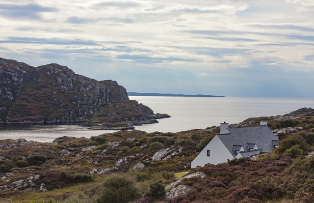 'Traditional white-washed crofter's cottage in idyllic Highland glen below dramatic cloudscape sweeping over wild mountain peaks, (Foto: Getty Images)