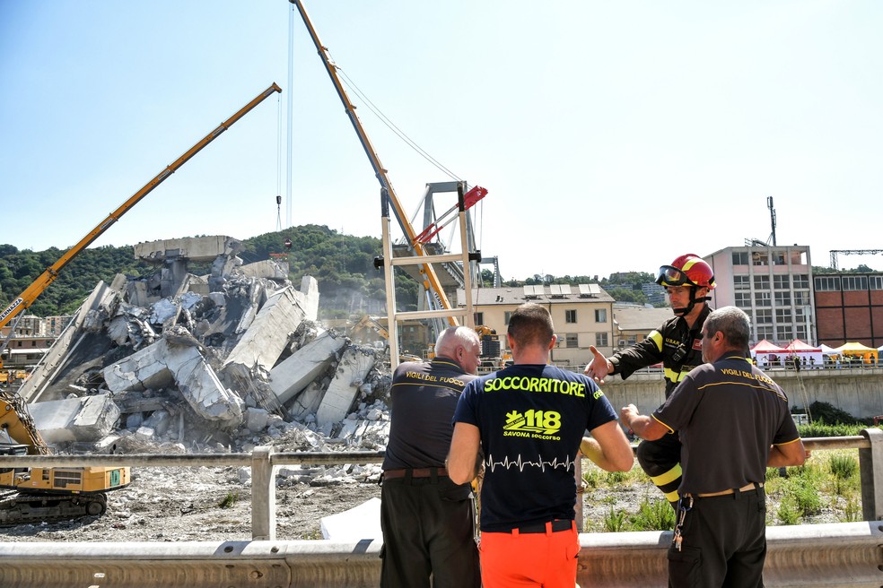 Voluntário distribui café aos bombeiros que trabalham nas buscas de vítimas sob os escombros da Ponte Morandi, em Gênova, nesta quinta-feira (16)  (Foto: Piero CRICIATTI/ AFP)
