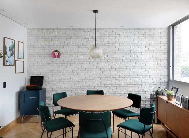 SALA DE JANTAR | A parede de tijolos brancos é o foco principal do ambiente integrado ao estar. Mesa redonda e cadeiras assinadas por Fernando Jaeger. Buffet da Westwing. Pendente da Collector 55 (Foto: Mariana Orsi / Divulgação)