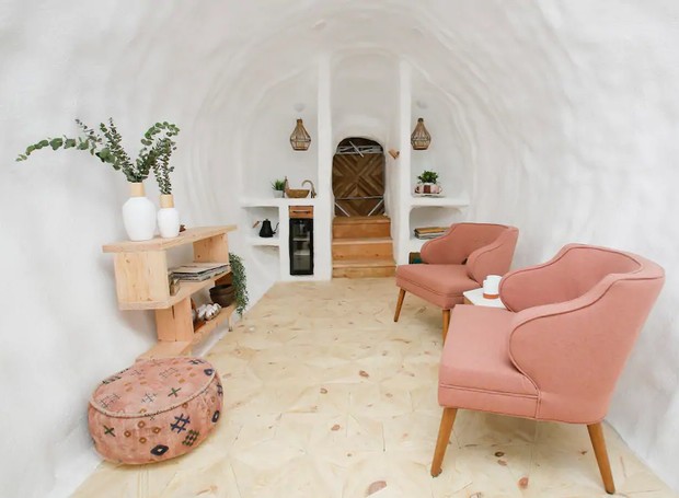 No interior, a paleta branca é levantada pelo rosa millennial das poltronas (Foto: Airbnb/ Reprodução)