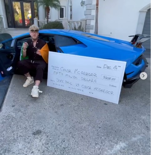 Jake Paul posando ao lado do cheque com a oferta de US$ 50 milhões por uma luta com Conor McGregor (Foto: Instagram)