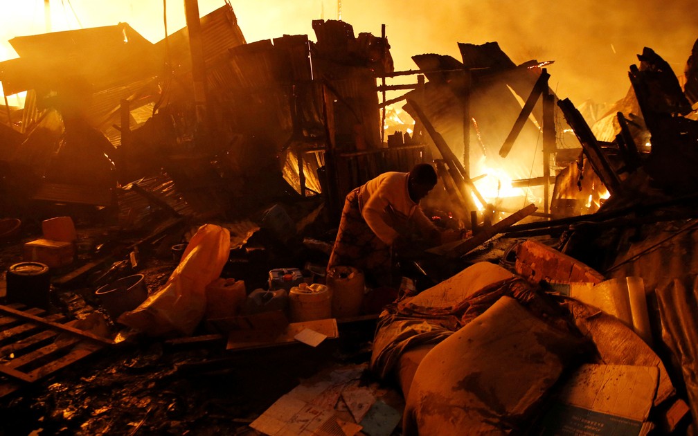 Moradora busca pertences nos destroços deixados por incêndio em favela de Nairobi, no Quênia, no domingo (28)  (Foto: Thomas Mukoya/ Reuters)