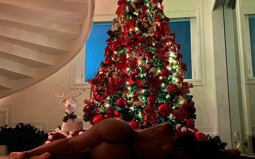 Iza posa nua em frente a árvore de Natal