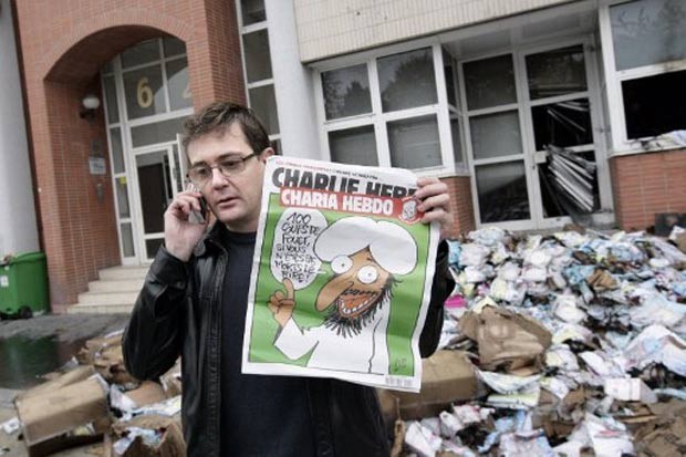 Le rédacteur en chef de Charlie Hebdo montre un dessin controversé lors de l'attentat de 2011 (Photo : Alexander Klein/AFP)