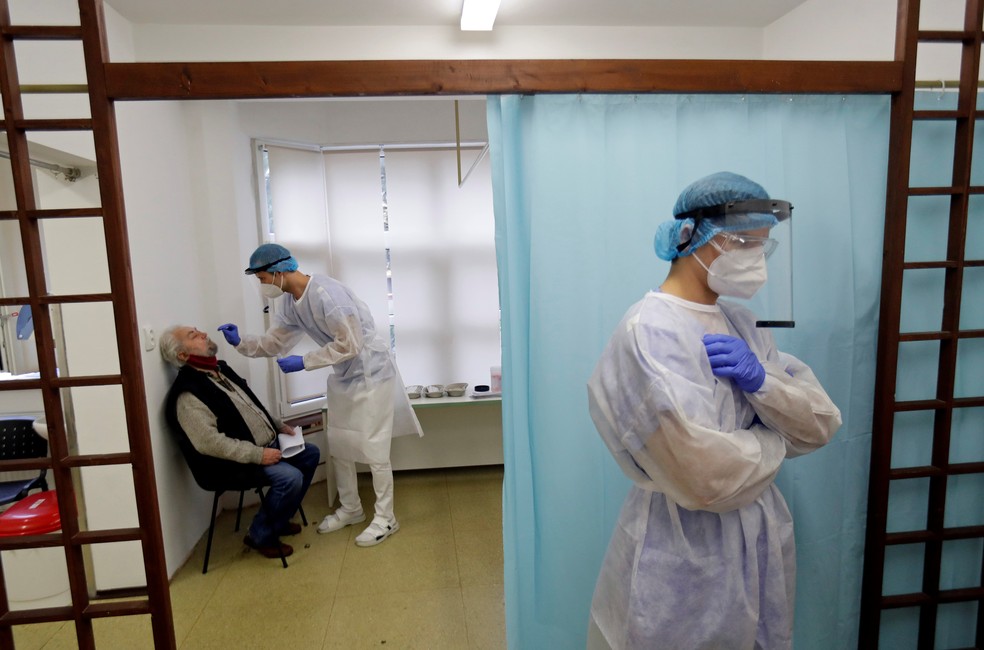 Profissional de saúde testa paciente para Covid-19 em Praga, na República Tcheca, enquanto outro profissional espera do lado de fora da sala de testagem, no dia 30 de outubro. — Foto: David W Cerny/Reuters