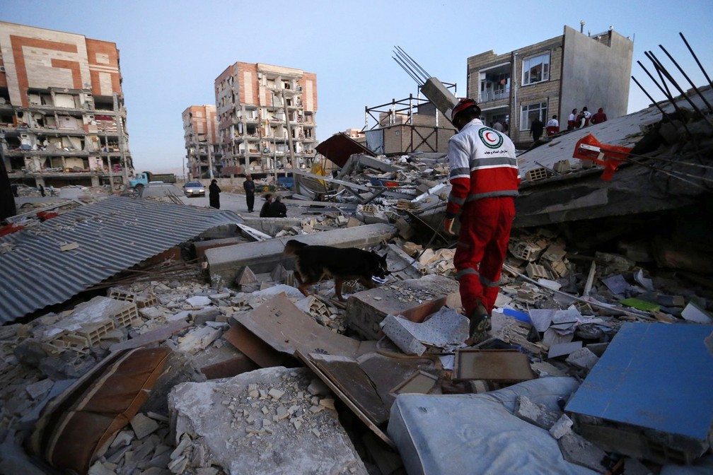 Funcionário do Crescente Vermelho realiza trabalho de busca para encontrar sobreviventes em destroços de prédio destruído na cidade de Sarpol-e-Zahab, após terremoto (Foto: Pouria Pakizeh/ISNA/AP)