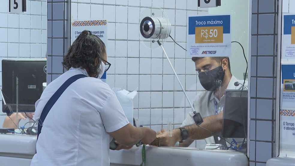 Passageira e funcionário usam máscaras em estação de metrô no DF — Foto: TV Globo/Reprodução