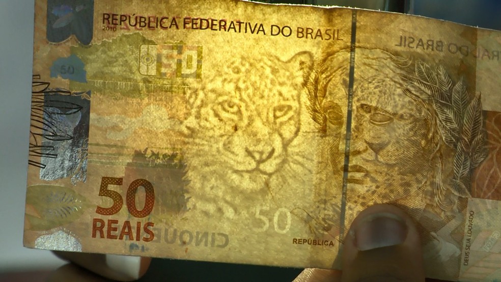 Nota de R$ 50 colocada contra a luz apresenta a marca d'água de uma onça e o número 50. — Foto: Reprodução/TV Gazeta