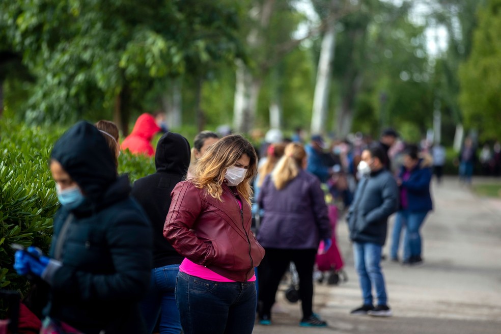 Pessoas fazem fila enquanto aguardam ajuda alimentar distribuída por voluntários em Madri, na Espanha, no sábado (16) — Foto: Manu Fernandez/AP 