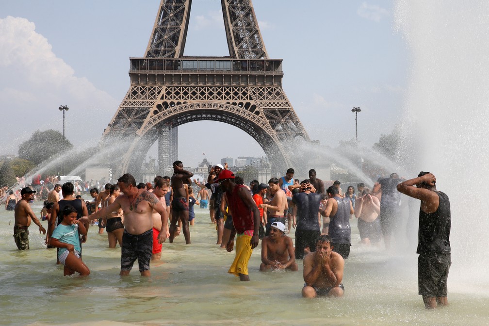 Pessoas se refrescam em fonte próxima à Torre Eiffel, em Paris. — Foto: Pascal Rossignol/Reuters