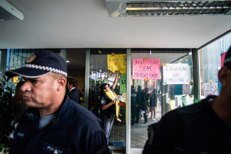 Policial retira cartazes colados no MEC â€” Foto: ReproduÃ§Ã£o/UNE