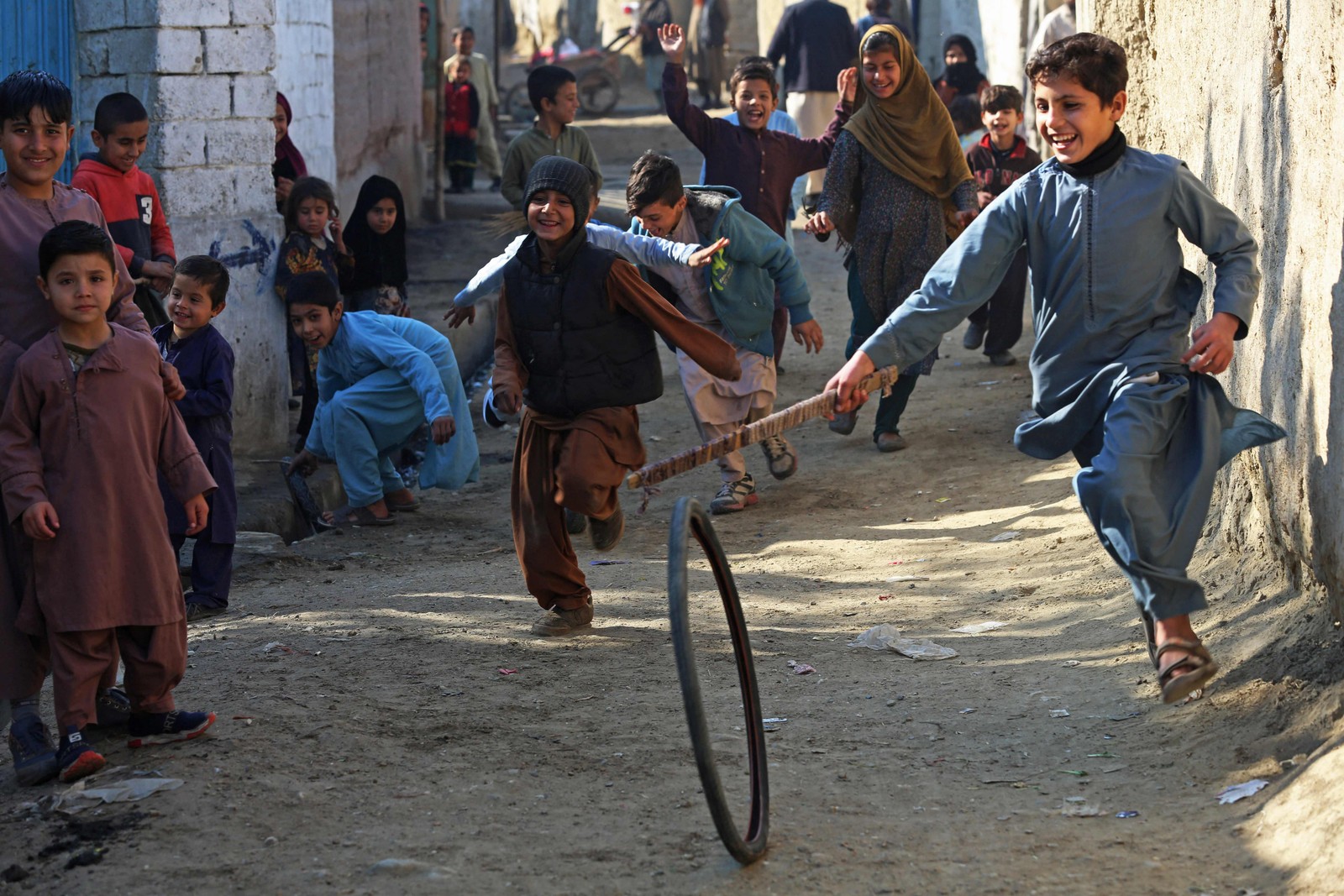 Crianças afegãs brincam com um pneu ao longo de uma rua em Jalalabad.  — Foto: AFP