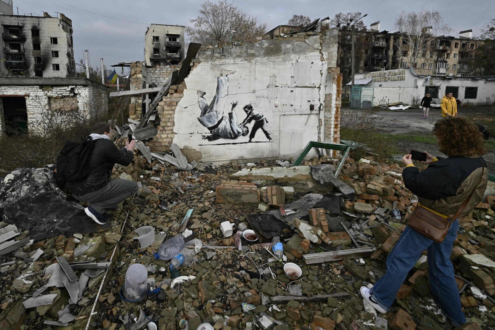 Ucranianos tiram foto de grafite 'estilo Banksy' que retrata uma criança derrubando um adulto com golpe de judô — Foto: Genya SAVILOV / AFP