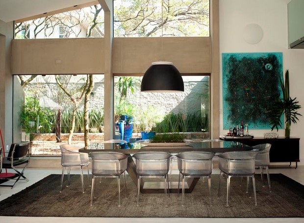 A sala de jantar, integrada ao living, tem mesa preta Calan da The Design Place. Cadeira papyrus acrílico cristal da Kartell. Arandela eclipse da Lumini (Foto: André Fortes/Divulgação)