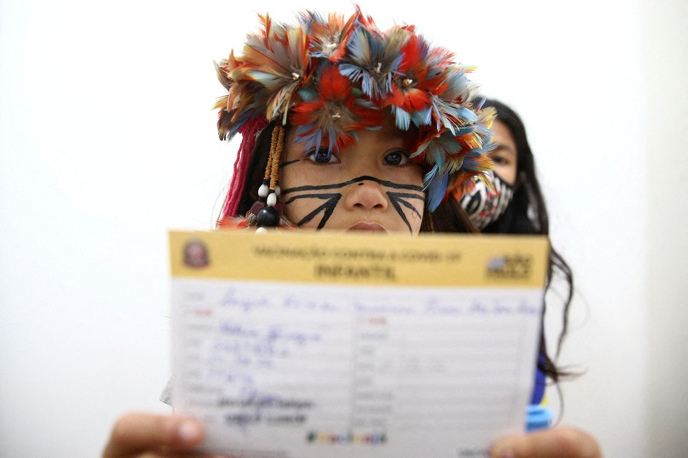 Na foto, Laysa Kerexu Mirim, menina indígena de 7 anos, aparece mostrando o cartão de vacinação contra a Covid-19 depois de ser imunizada em São Paulo, no dia 17 de janeiro. — Foto: Carla Carniel/Reuters