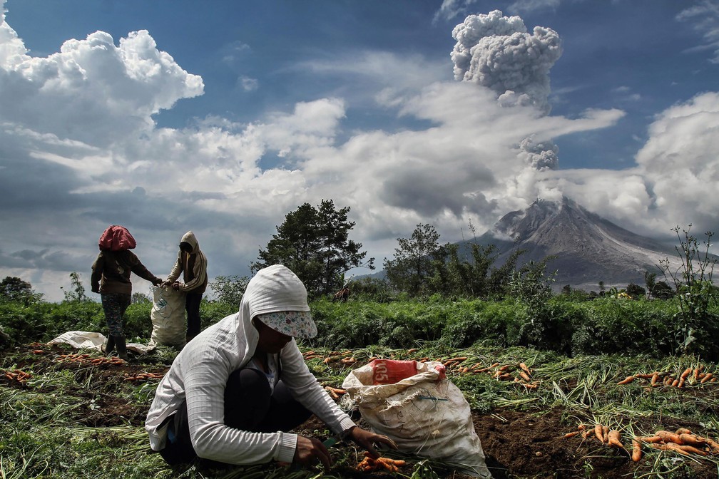 Agricultores trabalham em um campo perto do vulcão do monte Sinabung em Karo, na Indonésia (Foto: Ivan Damanik/AFP)