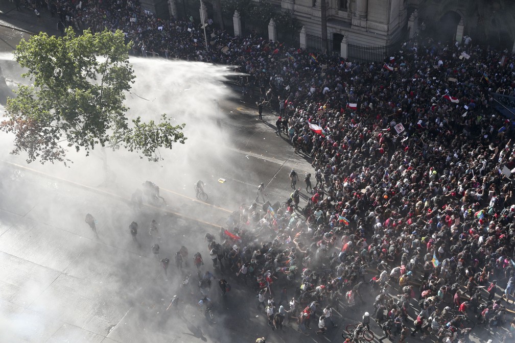 Policiais jogam água para dispersar manifestantes que protestavam no centro de Santiago, capital do Chile, nesta segunda-feira (28) — Foto: Esteban Felix/AP Photo