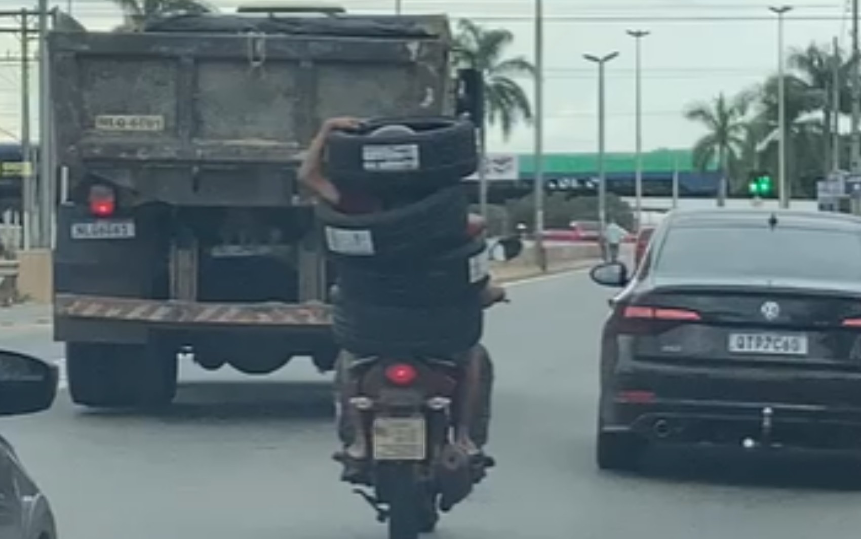 Garupa se 'veste' com quatro pneus para conseguir levá-los em moto, em Goiânia; vídeo