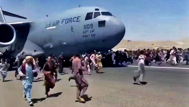 Pessoas correm na pista do aeroporto de Cabul tentando embarcar em um avião da Força Aérea dos Estados Unidos (Foto: BBC)