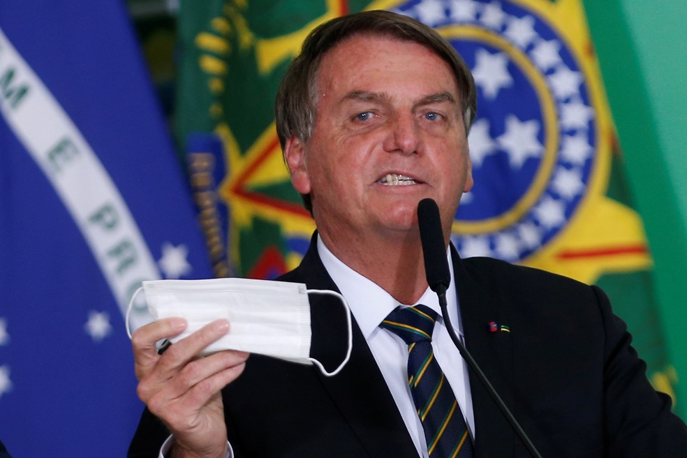Jair Bolsonaro segura máscara, que está fora do rosto, em evento no palácio do Planalto, em 10 de junho — Foto: Reuters/Adriano Machado