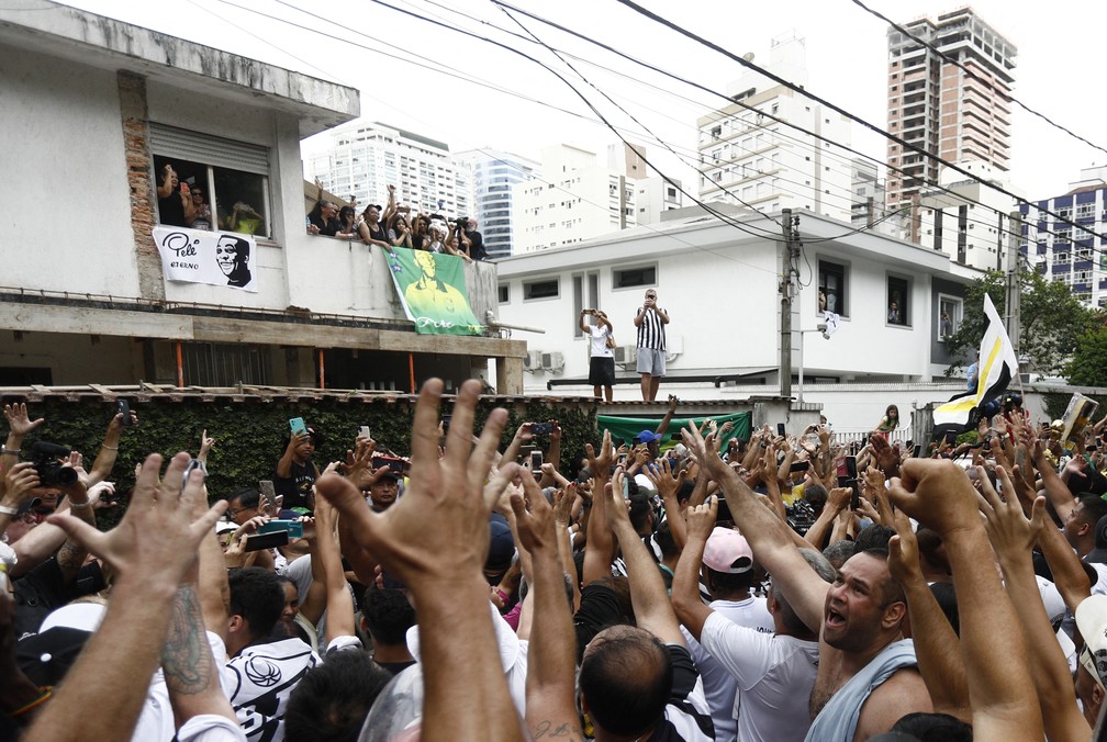 Multidão faz oração na janela do quarto de Dona Celeste, mãe de Pelé. — Foto: Diego Vara/Reuters
