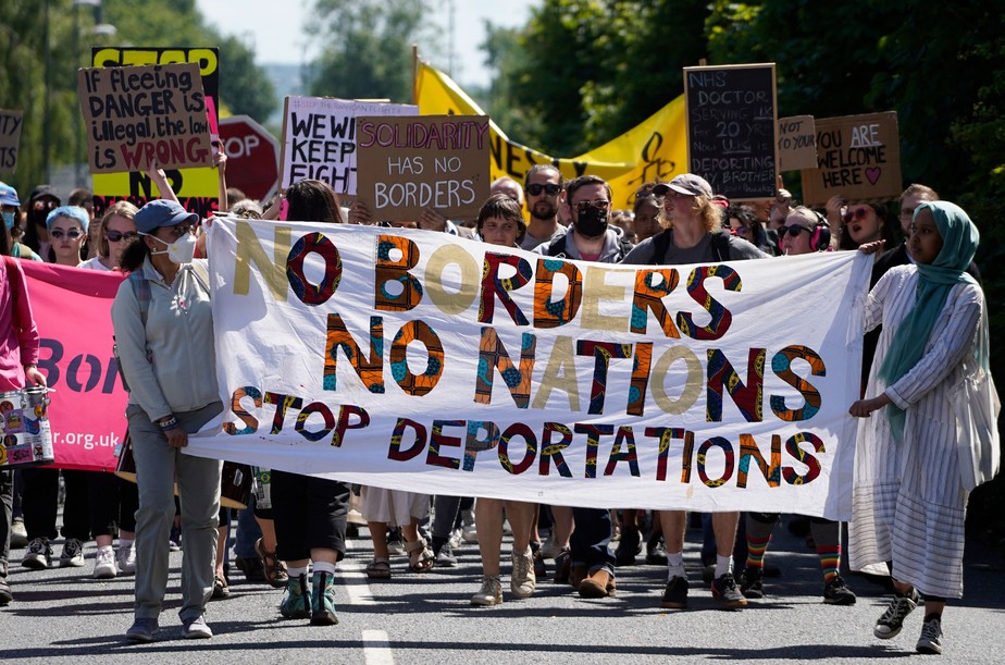 Manifestantes marcham em direção ao centro de remoção de imigrantes Brook House, ao sul de Londres, para protestar contra a intenção do governo britânico de deportar refugiados para Ruanda