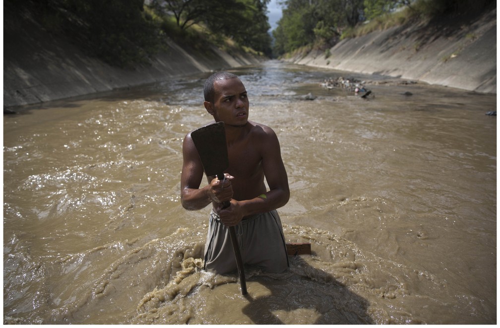 Ángel Villanueva 'garimpando' no poluído Rio Guaire, em Caracas (Foto: Ariana Cubillos/AP)