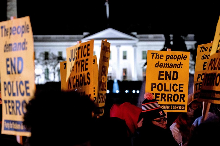 Manifestantes protestam em frente à Casa Branca, em Washington, com cartazes que pedem o fim da violência policial