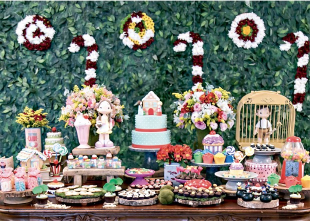 A mesa — A floresta onde os personagens se perderam é recriada tanto no painel de fundo quanto na mesa, com muita folhagem, troncos de árvores e flores (naturais e artificiais), além de diversos doces. Materiais como madeira, porcelana e latas também são (Foto: Thais Galardi/GNT)