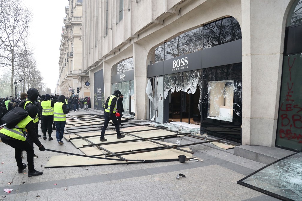 Coletes amarelos destroem vidraça da loja da Hugo Boss na avenida Champs-Elysées neste sábado (16)  — Foto: Zakaria Abdelkafi / AFP