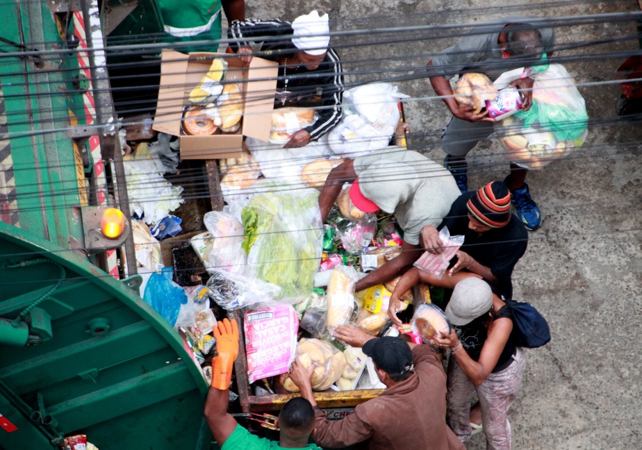 Rio de Janeiro (RJ), 08/08/2022 - LIXO/FOME/ALIMENTOS/RJ - Pessoas são flagradas recolhendo alimentos e produtos de caminhão de coleta de lixo descartados por supermercado na rua do Rezende, na região central do Rio de Janeiro, nesta segunda-feira, 8 de agosto de 2022. A mesma cena foi flagrada no mês passado. (Foto: Onofre Veras/TheNews2/Agência O Globo) Rio