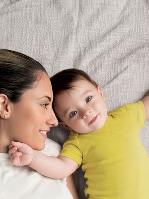 Mãe abraçando bebê na cama (Foto: Shutterstock)