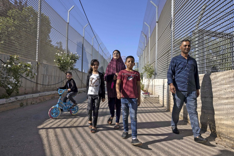 Saadat Gharib (direita) caminha com sua família entre as barreiras do exército israelense, em direção à sua casa, na Cisjordânia
