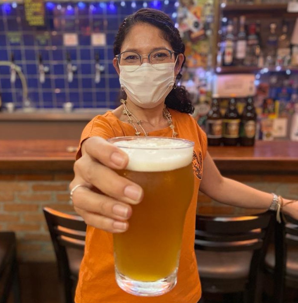 Eneide Gama com um copo da Cerveja Benedita, criada por ela e Melissa Miranda, em um bar em Pinheiros, na Zona Oeste de SP — Foto: Patrícia Figueiredo/g1 SP