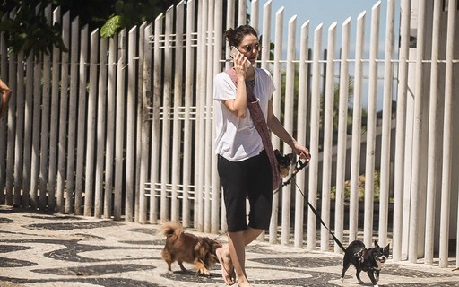 Isabelle Drummond passeia com cachorros na orla da praia
