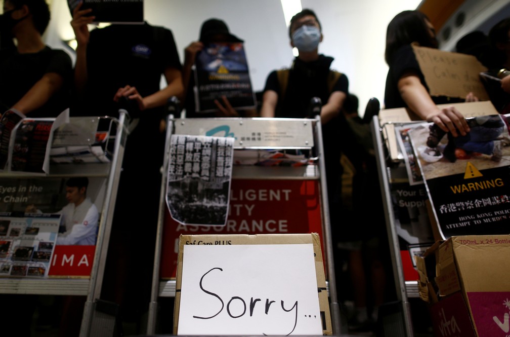 Manifestante exibe cartaz com a expressão ‘desculpe’ na barricada que bloqueia o acesso aos portões de embarque no Aeroporto Internacional de Hong Kong nesta terça-feira (13)  — Foto: Thomas Peter/ Reuters