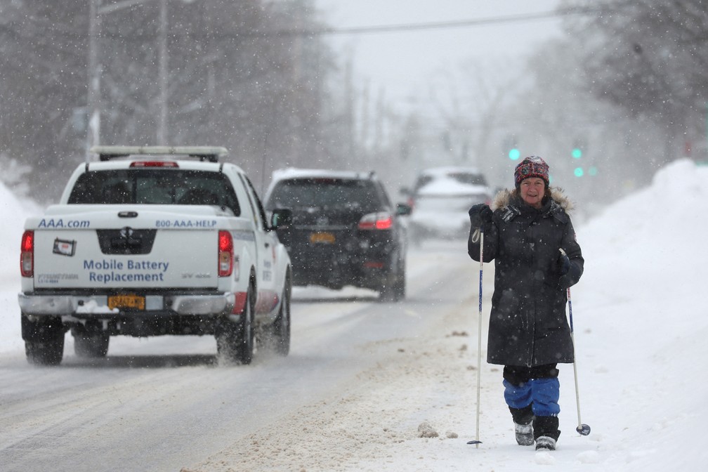 Uma mulher caminha na rua enquanto os carros passam após uma tempestade de inverno que atingiu a região de Buffalo, em Amherst, Nova York, EUA, nesta segunda-feira (26) — Foto: Reuters/Brendan McDermid
