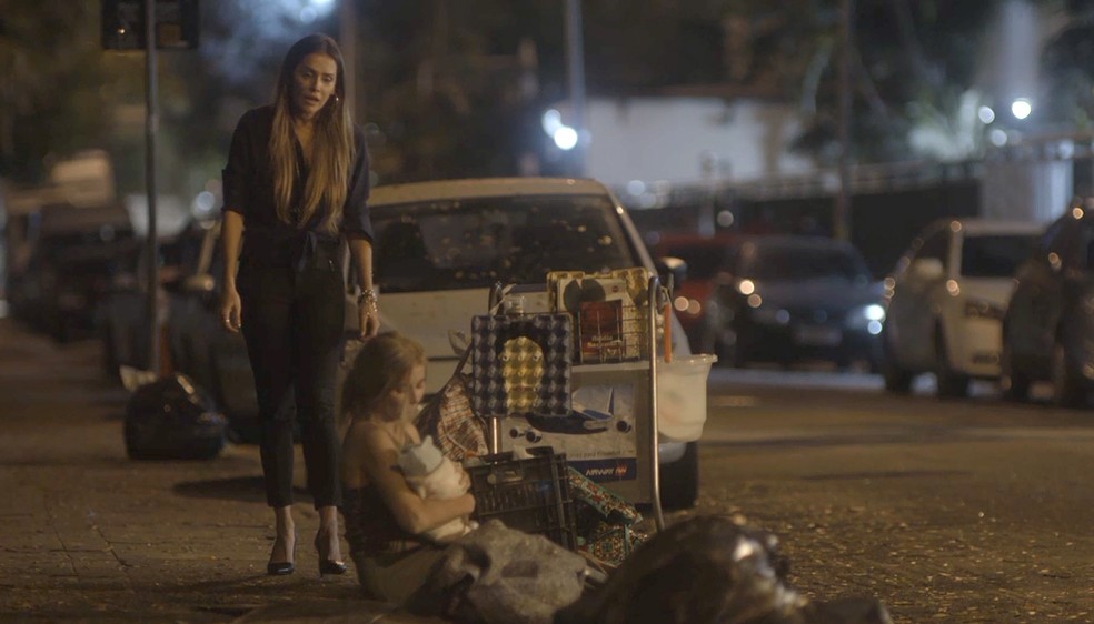 Desorientada, Karola vaga pelas ruas e se aproxima de uma mulher com um bebê — Foto: TV Globo