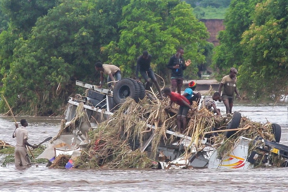 Pessoas sobem em veículo tombado durante tempestade Ana no Malauí em foto de 26 de janeiro de 2022 — Foto: AP Photo