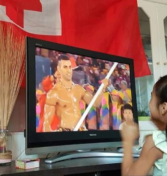 Pita Nikolas Taufatofua porta-bandeira de Tonga, sobrinha vendo TV (Foto: Reprodução)