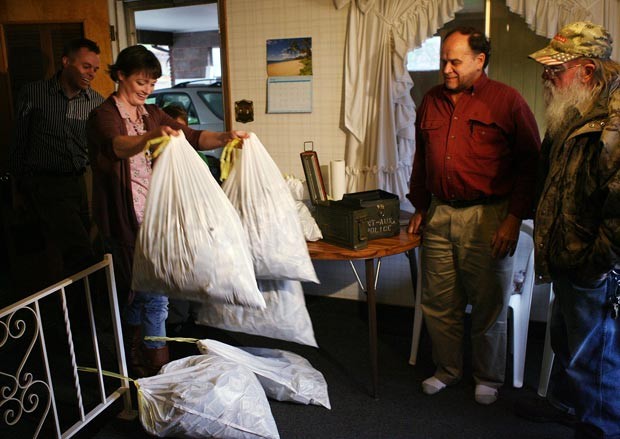 Josh e Tara Ferrin mostram as sacolas de dinheiro para Dennis e Kay Bangerter. (Foto: Brian Nicholson/Deseret News/AP)