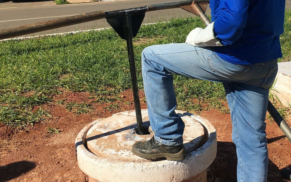  Técnico da Caesb espera para girar válvula de registro e liberar o fluxo de água (Foto: Luiza Garonce/G1)