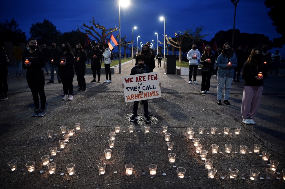 Membros da comunidade armena em Tessalônica, na Grécia, marcam o 106º aniversário do início do massacre de armenos pelo Império Otomano. O cartaz diz 'nós somos poucos, mas eles nos chamam de armenos'. — Foto: Sakis Mitrolidis / AFP