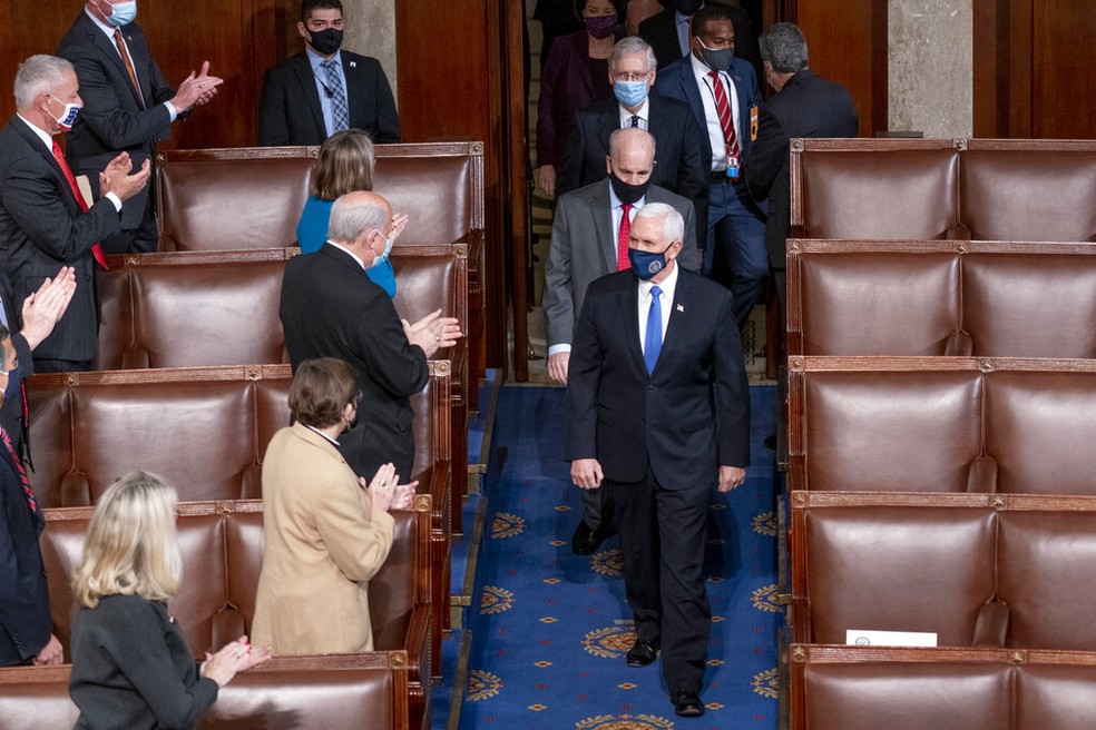 Mike Pence, vice-presidente dos EUA, e Mitch McConnell, líder republicano no Senado (acima, de máscara azul claro), chegam à sessão de contagem de votos no Congresso dos EUA nesta quarta-feira (6) — Foto: Andrew Harnik/AP Photo